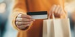 © Kamonwan - Person holding credit card and shopping bag in a modern retail environment