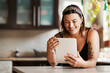© Malambo/peopleimages.com - Happy woman, reading and tablet in kitchen for ebook, relax and streaming media on internet. Girl, smile and tech in home for funny blog website, comedy news and social networking with connectivity