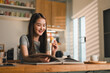 © kenchiro168 - young woman enjoys pastry while reading book in cozy kitchen. warm sunlight filters through window, creating cheerful and inviting atmosphere