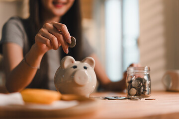 Saving money is important habit, as shown by woman placing coin into piggy bank while surrounded by coins and jar filled with more coins. This scene reflects financial responsibility and planning for