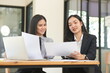 © panomporn - Happy Asian business people working together using laptop and tablet in office.