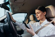 © SHOTPRIME STUDIO - Woman, car, cell phone, driver a woman is seated in the driver's seat of a car, holding a cell phone and intently looking at its screen
