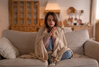 © YarikL - A woman freezes in winter. A young girl in warm woolen socks and wrapped in a blanket tries to keep warm while sitting on the sofa at home. Keep warm.