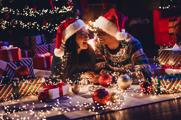 Portrait of two young people couple have fun laugh celebrate xmas new year garland lights flat indoors