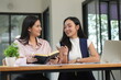 © panomporn - Group of happy Asian business people having a meeting at the office. Two women working together using modern laptops.