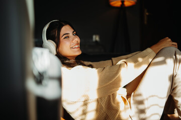 Young caucasian woman enjoying music on wireless headphones at home	