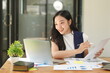 © panomporn - Happy Asian business people working together using laptop and tablet in office.