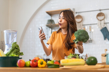 Portrait happy beauty slim healthy asian woman use phone and vegan food healthy fresh vegetable and fruit in kitchen.diet, vegetarian, eating, fruit, wellness, health, green food.Fitness, healthy food