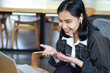 © M Alfan Setyawan - smiling asian woman doing presentation via virtual online meeting using laptop in indoor cafe