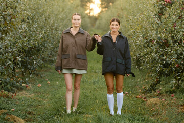 two stylish girls in jackets at a fashion show in the apple orchard. fashion show in the garden