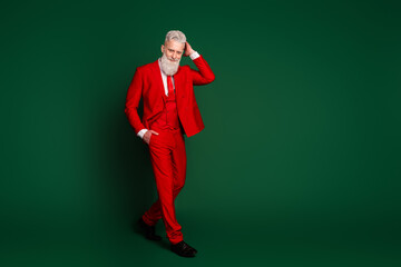 Full length portrait of elegant stylish santa touch hairstyle walk empty space red new year suit isolated on green color background