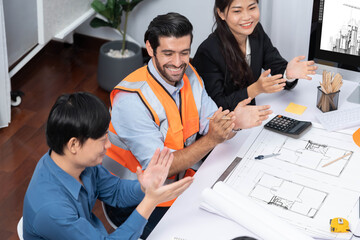 Diverse group of civil engineer and client feels excited and applauding after successful agreement on architectural project, review construction plan and building blueprint at meeting table.Prudent