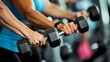 © Tadeusz - Close-up of two women working out with dumbbells in a gym setting.