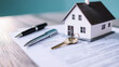 © Maksym - A miniature house placed on top of mortgage application papers, with keys and a pen nearby, evoking the process of real estate investment and homeownership.