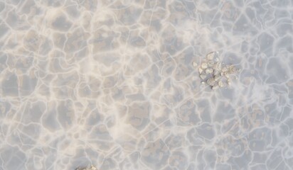 Clear water surface reflecting sunlight and underwater rocks, top view, 3D illustration.