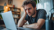 © Bonsales - Struggling young man faces stress and frustration while working from home office