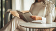 © alisluch - Person relaxing while reading a book in a cozy, minimalist space with a vase of dried flowers on the table. Copy space