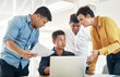 © peopleimages.com - Business people, documents and laptop with team in meeting for discussion, project or planning at office. Young, group or employees with paperwork or computer for deadline, tasks or schedule at desk