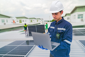 Wall Mural - a worker in protective gear uses a laptop while inspecting solar panels on a rooftop. the image emph