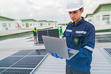 Wall Mural - a worker in protective gear uses a laptop while inspecting solar panels on a rooftop. the image emph