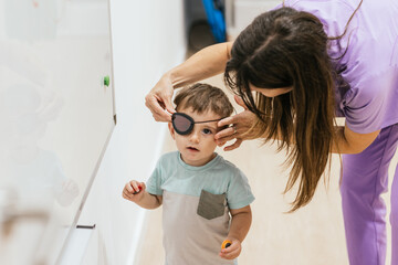 optometrist placing eye patch on toddler boy for treatment