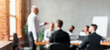 © Prostock-studio - Corporate Meeting Concept, Blurred Background. Unrecognizable Businessman Giving Speech During Meeting With Coworkers In Modern Office.