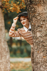 A woman in vintage clothes and a hat in an autumn park. Retro style.