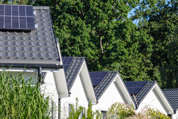 row of modern houses with solar panels in green suburban environment
