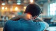 © olga_demina - Young businessman is holding his neck in pain while working on his laptop in a coworking space, suggesting the negative impact of sedentary work on health
