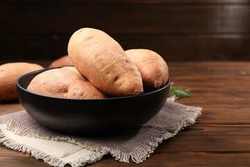 Sticker - Fresh sweet potatoes in bowl on wooden table, closeup. Space for text