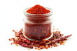 © Ivan Traimak - A close-up view of red chili powder in a glass jar surrounded by dried red chilies placed on a white background. Generative AI
