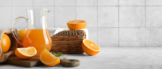 Wall Mural - Jug of fresh orange juice and wicker box with fruits on white table