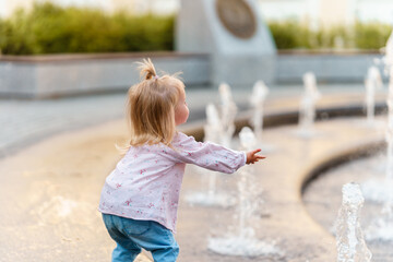 Caucasian Child toddler girl walks with her father on a sunny summer day walking by the fountains.