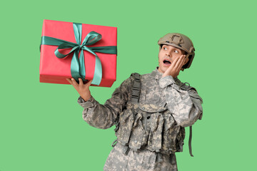 Wall Mural - Male soldier with gift box on green background