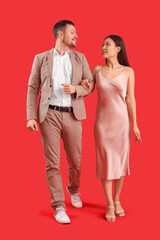 Canvas Print - Young couple walking on red background