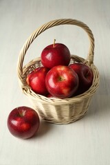 Wall Mural - Fresh ripe red apples in wicker basket on white wooden table