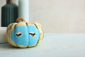 Canvas Print - Pumpkin with clay mask and different cosmetic products on light blue table against grunge background