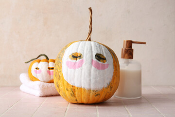 Wall Mural - Pumpkins with clay masks, towel and cosmetic product on pink tile table against grunge background