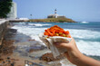 © zigres - Acaraje in Salvador de Bahia, Brazil. Brazilian traditional dish Acaraje street food from Northeast Brazil with Farol da Barra Lighthouse and Bay of All Saints, Salvador de Bahia, Brazil.