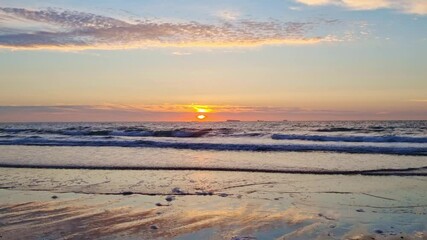 Wall Mural - A serene sunset scene with a vibrant sun setting over calm ocean waves. the sky features soft clouds with warm hues reflecting on the wet sand, creating a peaceful coastal ambiance suitable for relaxa