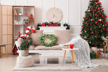 Wall Mural - Cozy sofa with mistletoe wreath, Christmas tree and coffee table in interior of living room