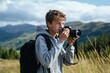 © Maelgoa - Teenage boy with short brown hair, wearing a hoodie and shorts, taking photos with a camera in the mountains 1