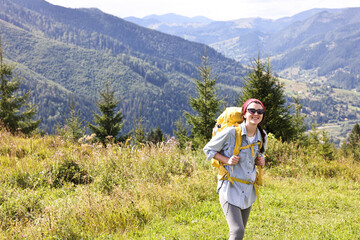 Happy young hiker with backpack in mountains