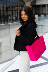 Wall Mural - Enjoying shopping and buying new clothes as hobby. Happy attractive woman is going shopping on Black Friday. Flirtatious woman in white dress and black jacket is walking in city store.