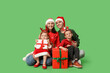 © Pixel-Shot - Happy family in Christmas clothes and gifts on green background
