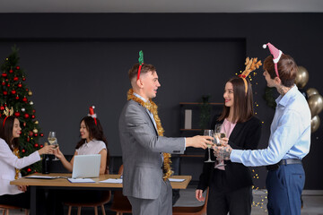 Wall Mural - Young coworkers with champagne celebrating New Year at corporate party in office