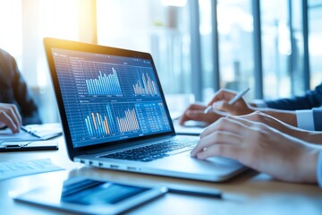 Two professionals analyzing financial data on a laptop in a bright office setting, showcasing business trends and market insights.