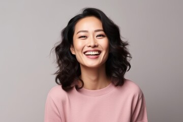 Wall Mural - Portrait of a beautiful young asian woman smiling against grey background