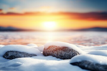 Canvas Print - A rocky shoreline with snow and a beautiful sunset in the background