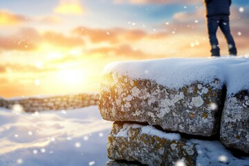 Poster - A person stands on a snow-covered rock, looking out at the sunset